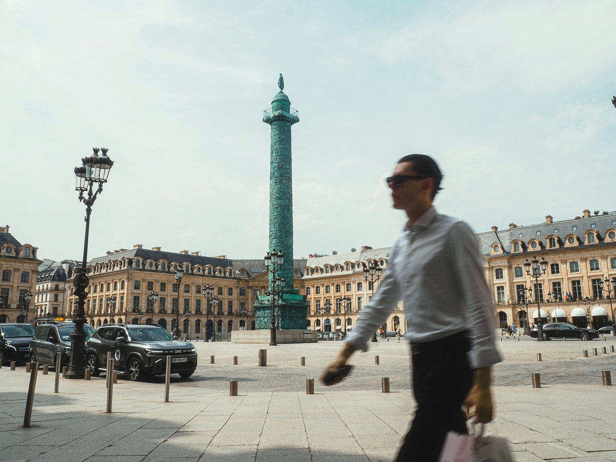 Silhouette masculine traversant la Place Vendôme à Paris, architecture parisienne et atmosphère mode